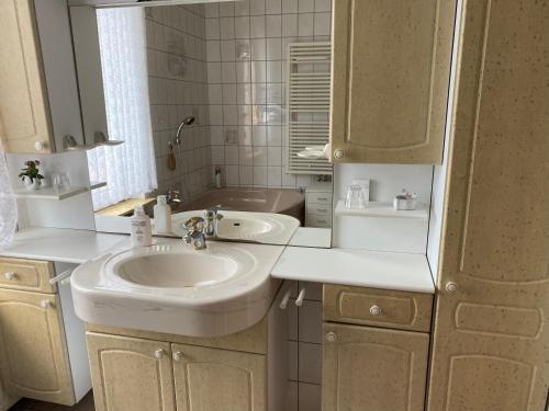 La salle de bains blanche est pourvue d'un lavabo et d'un miroir. dans l'établissement Gästehaus Seestern, à Cuxhaven