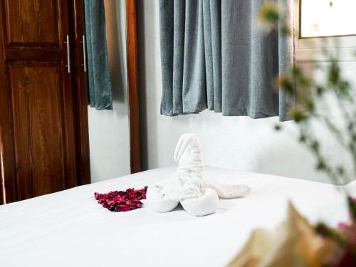a pair of white shoes and flowers on a bed at Ayouz House Hotel in Dakhla