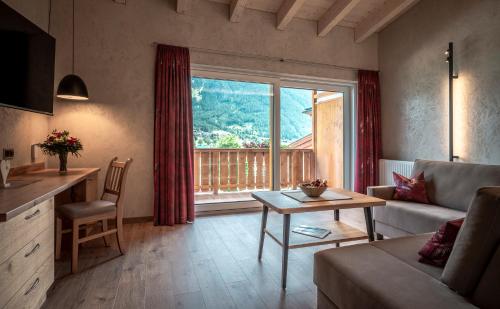 a living room with a couch and a table and a window at Seehotel St Hubertus in Pertisau
