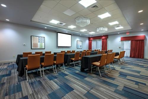 a conference room with tables and chairs and a screen at Holiday Inn Express-International Drive by IHG in Orlando