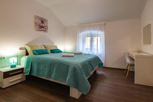 a bedroom with a bed with a green blanket and a window at Antique center Pula in Pula