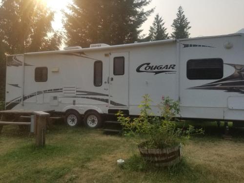 a white camper parked in a field next to a table at Noah's Ark Campground in Revelstoke
