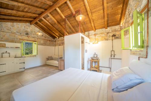 a bedroom with a large white bed in a room at Vinovassilema Stone Cottage in Atsoupádhes