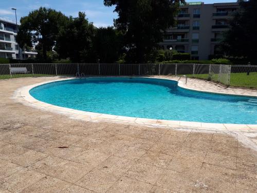 a large swimming pool with blue water in a yard at Studio bord de mer in Saint-Laurent-du-Var