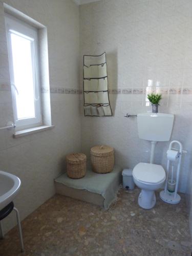a bathroom with a toilet and a sink and a window at Apartamento Rosa in Vila Nova de Milfontes