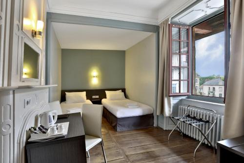 Pierre-BuffièreにあるLogis Hotel Auberge Dupuytrenのベッド2台とデスクが備わるホテルルームです。