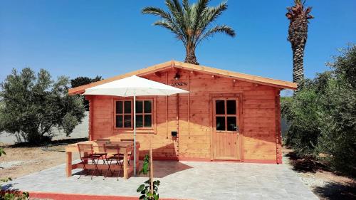 una piccola cabina in legno con tavolo e ombrellone di Cyprus Glamping Park ad Ayios Theodhoros