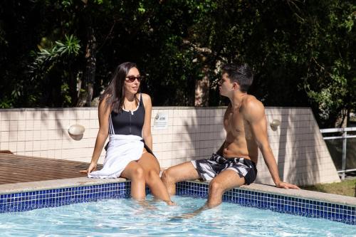a man and a woman sitting in a swimming pool at Pousada Aguas Claras in Búzios