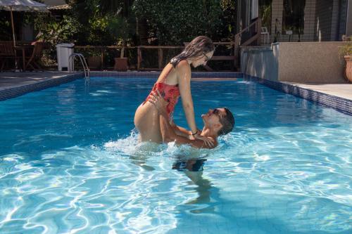 a man and a woman in a swimming pool at Pousada Aguas Claras in Búzios
