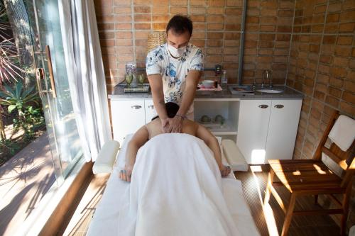 a man in a face mask cutting a persons leg at Pousada Aguas Claras in Búzios