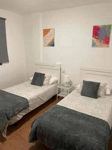 two beds in a room with white walls at Apartamento los Rostros in La Santa