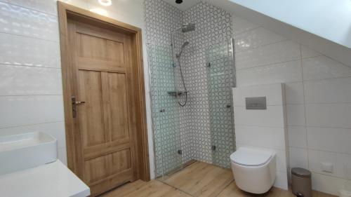 a bathroom with a toilet and a wooden door at Guliwer in Niechorze