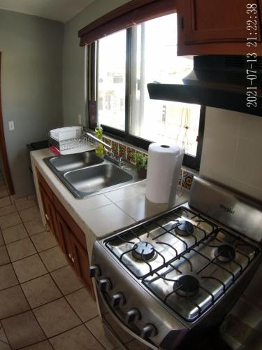 a kitchen with a stove and a sink and a window at Sofia Hostel Cabo in Cabo San Lucas