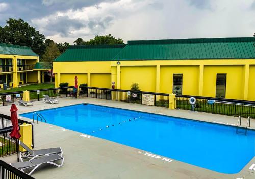 a large swimming pool in front of a yellow building at Red Carpet Inn Kinston in Kinston