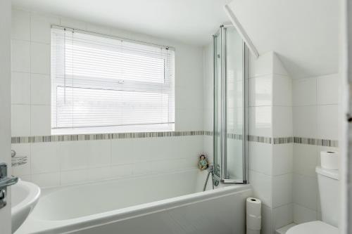a bathroom with a tub and a toilet and a window at Lima Apartments Ltd-4 Beds-Large property -Long Stay Deal-Business-Parking in Bournemouth