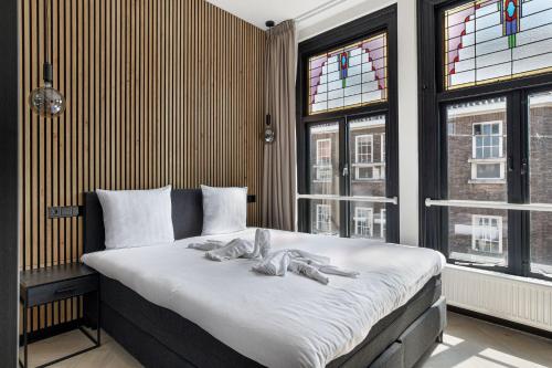 Haarlem Apart Hotel في هارلم: غرفة نوم بسرير وملاءات بيضاء ونوافذ