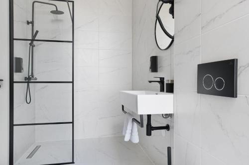 a white bathroom with a sink and a shower at Haarlem Apart Hotel in Haarlem