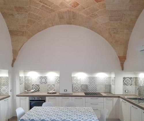 una cucina con armadi bianchi e tavolo con sedie di Villa Pescoluse a Marina di Pescoluse