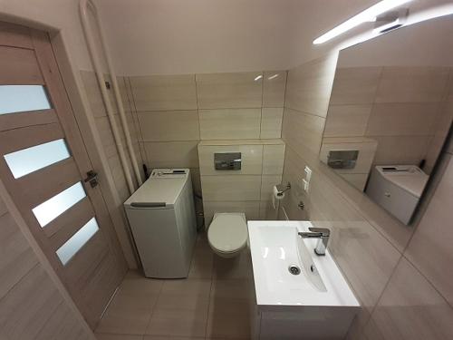 La salle de bains est pourvue de toilettes blanches et d'un lavabo. dans l'établissement MINILOFT Studio Centrum, à Suwałki
