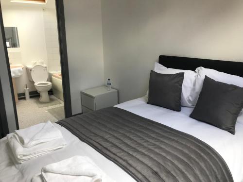 a bedroom with a bed and a bathroom with a toilet at Ty'r Bont Studios in Newtown
