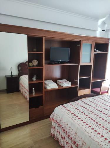 a bedroom with a bed and a tv on a shelf at Apartamento do Paim in Ponta Delgada
