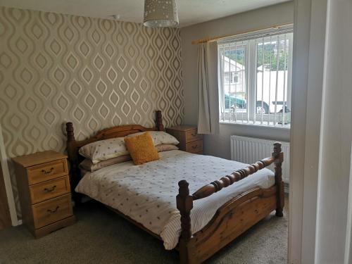 sypialnia z drewnianym łóżkiem i oknem w obiekcie En-suite Bedroom in a quiet bungalow w mieście Porthmadog
