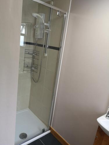 La salle de bains est pourvue d'une douche avec une porte en verre. dans l'établissement En-suite Bedroom in a quiet bungalow, à Porthmadog