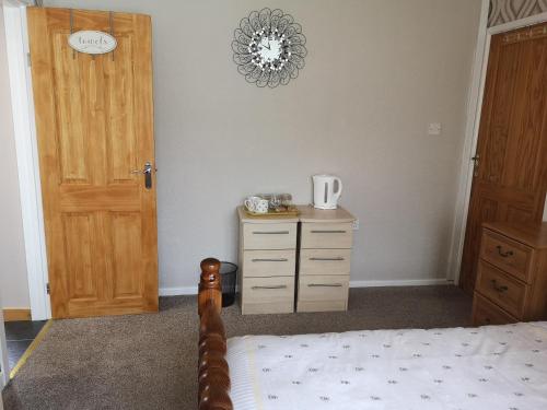 a bedroom with a bed and a dresser and a door at En-suite Bedroom in a quiet bungalow in Porthmadog