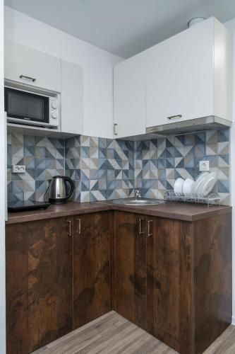 a kitchen with wooden cabinets and a microwave at Апартаменти MYFREEDOM поруч із метро Шулявська in Kyiv