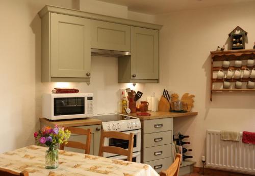 a kitchen with green cabinets and a table with flowers at Drumena Cottage in Kilcoo