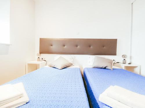 a bedroom with two beds with blue sheets and pillows at GOLD SUITE T2-PRAIA DO FURADOURO in Ovar