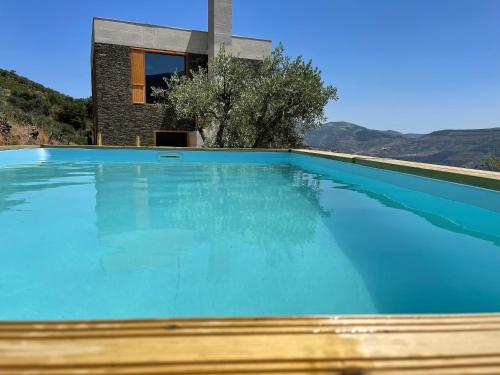 a swimming pool with blue water in front of a house at Casa do Arco by Douro Exclusive in São Cristóvão do Douro