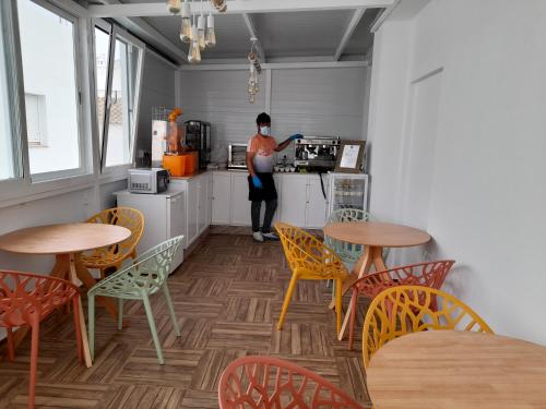 a woman in a kitchen with tables and chairs at Hostal Casandra - antiguo Hostal Los Valencianos in Conil de la Frontera