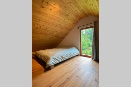 Le chalet des carrières في Chastre-Villeroux-Blanmont: غرفة نوم في منزل شجرة مع سرير ونافذة
