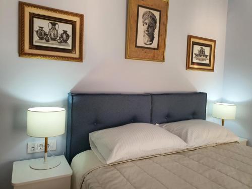 パルガにあるFlisvos sea view roomsのベッドルーム1室(ベッド1台、ランプ2つ、壁に絵画付)