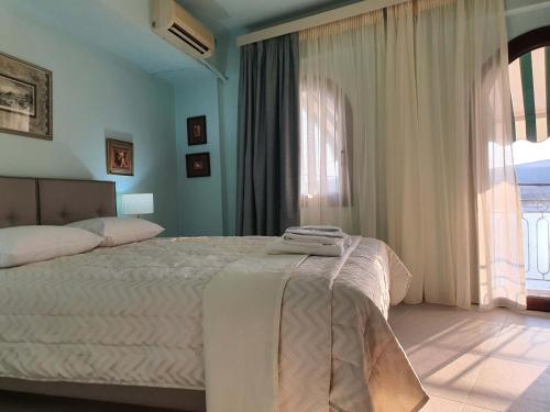 a bedroom with a bed and a large window at Flisvos sea view rooms in Parga