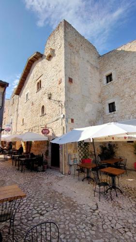 a building with tables and umbrellas in front of it at IL BORGO DI ROCCA CALASCIO in Calascio