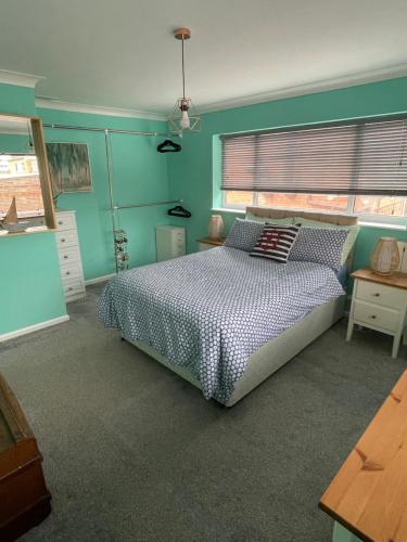 a bedroom with a bed and a blue wall at Seagull’s View in Lytham St Annes