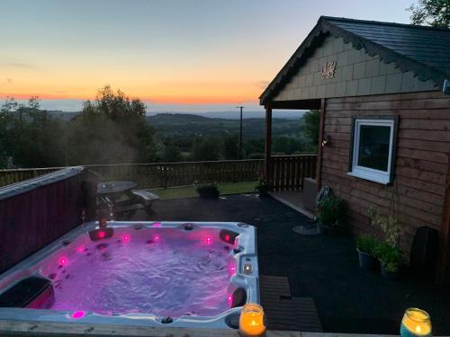 a hot tub with pink lights in a backyard at Kabin in the woods with Hot Tub in Llandybie
