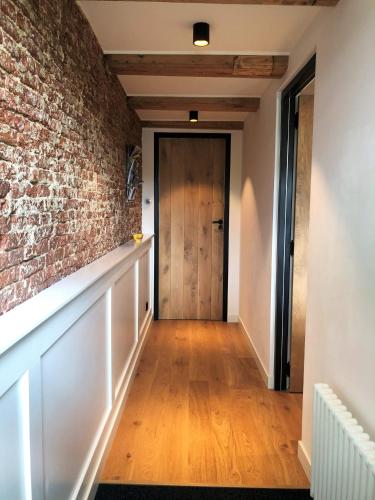 a hallway with a brick wall and a wooden door at 23 SouS in Amsterdam