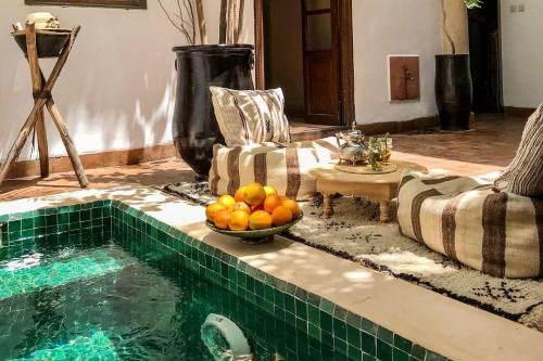 a swimming pool with a bowl of oranges in a living room at Riad Dar Zaman in Marrakesh