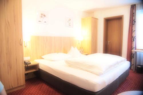 a bedroom with a bed with white sheets and pillows at Hotel am Bad in Tübingen