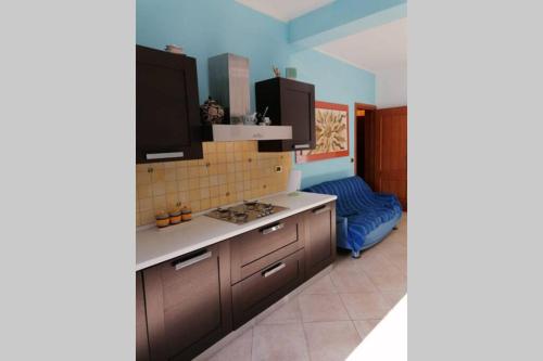 a kitchen with brown cabinets and a blue wall at Appartamento U scrusciu ro mari in Marzamemi