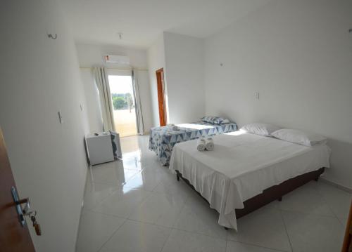 1 dormitorio con 2 camas y TV. en Pousada Central en Barreirinhas
