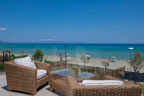 a patio with wicker chairs and a table and the beach at Alas Suites in Alykes