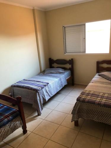 a room with two beds and a window at Aconchego - lar doce lar in Poços de Caldas
