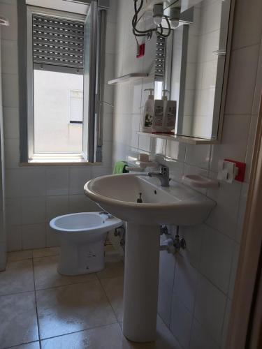 a white bathroom with a sink and a toilet at Emilù a mare in Schiavonea