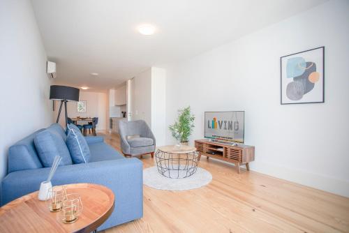 a living room with a blue couch and a table at Liiiving in Porto - City View Apartments in Porto