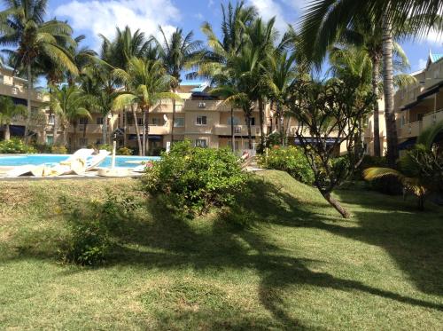 a person laying on the grass next to a swimming pool at Résidence le Dattier in Flic-en-Flac