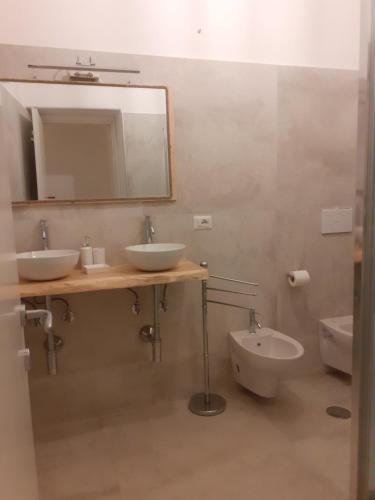 a bathroom with two sinks and a mirror and a toilet at arco del sacramento casa vacanze in Benevento
